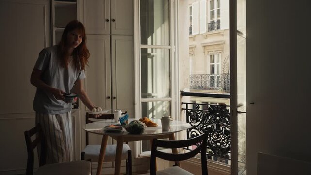 Red-haired woman preparing breakfast in parisian apartment