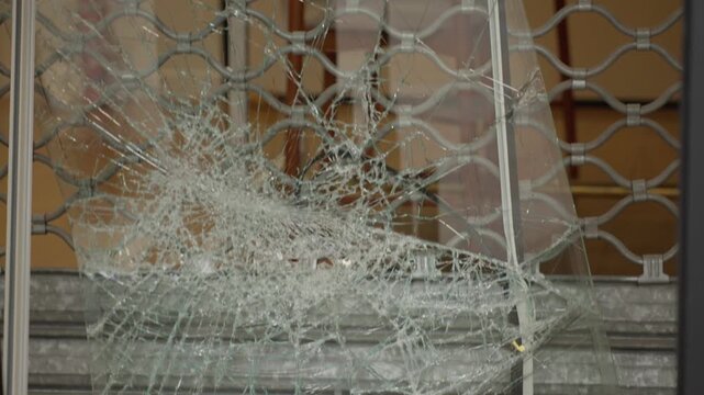 Shattered glass window with metal security gate after paris protest riot