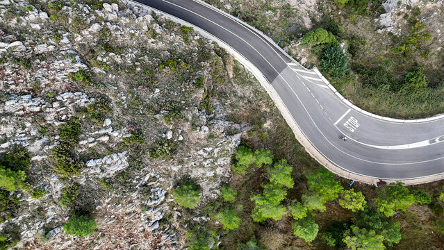 Aerial view of the winding road at Mirador del Coll de Rates de Parcent, surrounded by rocky terrain and pine trees, Alicante, Valencian Community, Spain.
