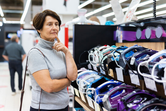 Elderly woman chooses iron in store