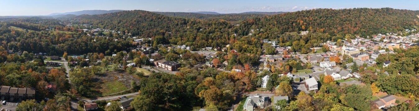 Aerial view of the town of Berkeley Springs surrounded by vibrant autumn foliage, rolling hills, and historic buildings in Berkeley Springs, West Virginia, United States.