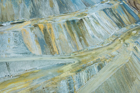 Aerial view of Bingham Copper Mine, showing massive terraced open-pit excavation with exposed rock layers, mineral deposits, and dirt haulage roads in Salt Lake County, Utah, United States.