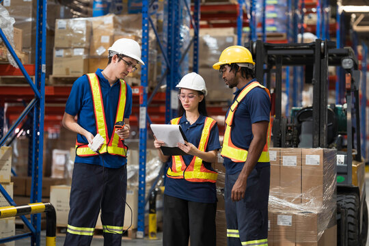 Warehouse workers, warehouse storage and logistics. Professional multiethnic team of warehouse workers discussing logistics plan and checking stock control while working in storage warehouse