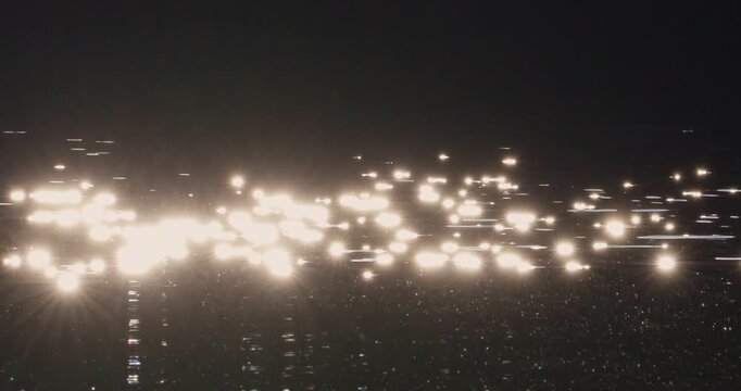 Bright sparkling sun glints and starburst reflections flickering on dark water surface in backlight