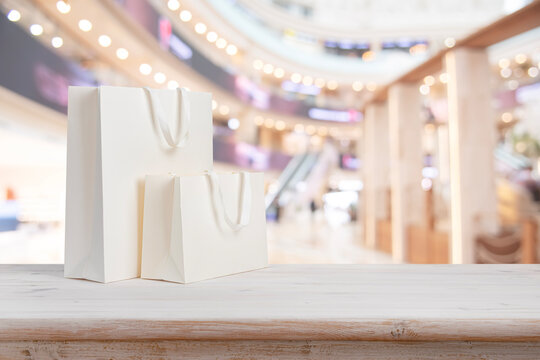 White paper shopping bags on table with blurred shopping mall interior background