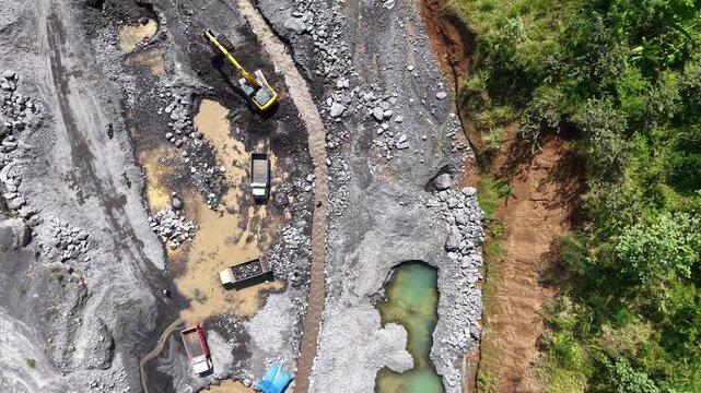 High angle drone view of heavy machinery harvesting natural gravel deposits from a solidified dry lava field below the volcano Mount Semeru at Lumajang