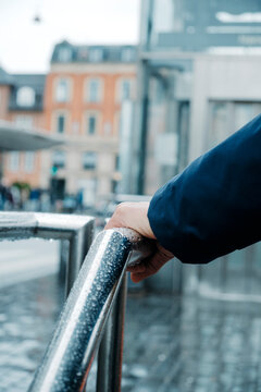 a man rests a hand on a wet railing in Copenhagen