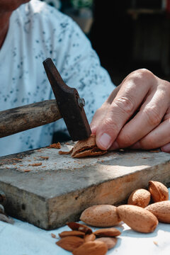 close-up of a man cracking an almond with a hammer