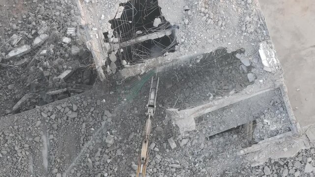 Excavator with hydraulic hammer dismantling a building at a construction site