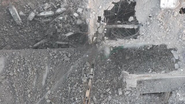 Excavator with hydraulic hammer dismantling a building at a construction site