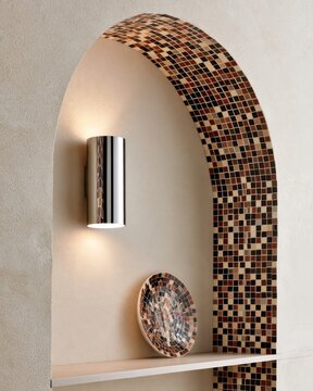Closeup of chrome wall sconce in arched mosaic niche with warm light for interior design background and poster