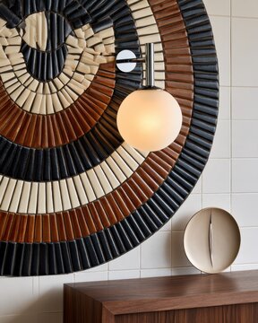 Circular mosaic tile medallion with concentric ceramic fans and globe wall sconce for interior design background and decorative detail