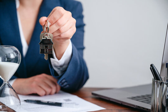 Real estate agent holding house keys in close-up, copy space