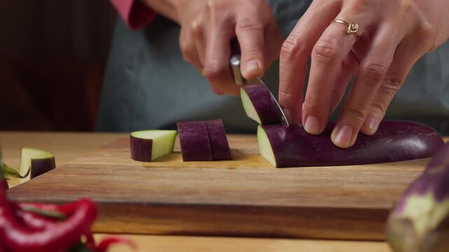 Cutting a Fresh Purple Eggplant on a Wooden Cutting Board