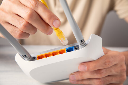 Man plugging internet cable into wifi router.