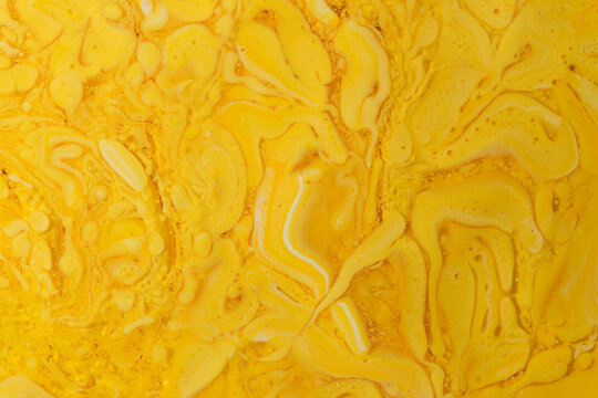 Textured liquid art background with rich yellow and white paint swirls, bubbles, and droplets.