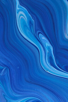 Vertical blue fluid acrylic paint texture featuring swirling marble patterns and rich tones.