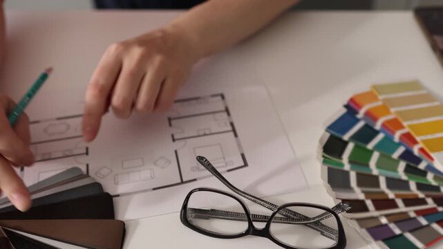 Interior designer selects wood material and annotates plan in design studio
