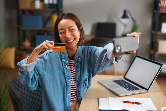 Woman holding credit card and smartphone for online shopping at home