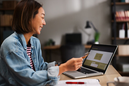 Woman shopping online with a credit card and laptop at home