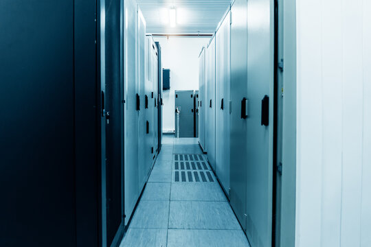 Server room corridor lined with equipment cabinets for data center infrastructure, cloud computing, secure information storage and enterprise network operations.
