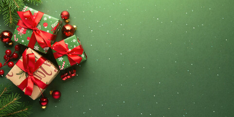Naklejka na ściany i meble Merry Christmas and Happy Holidays greeting card, frame, banner. New Year. Red Christmas ornaments and gifts, presents on green background top view. Xmas holiday festive theme. Christmas decoration