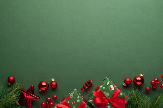 Merry Christmas and Happy Holidays greeting card, frame, banner. New Year. Red Christmas ornaments and gifts, presents on green background top view. Xmas holiday festive theme. Christmas decoration