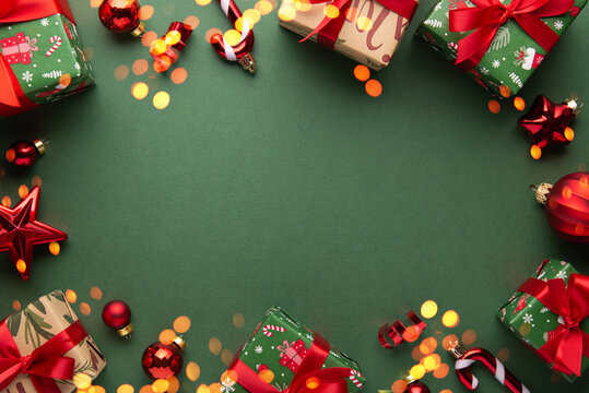 Merry Christmas and Happy Holidays greeting card, frame, banner. New Year. Red Christmas ornaments and gifts, presents on green background top view. Xmas holiday festive theme. Christmas decoration