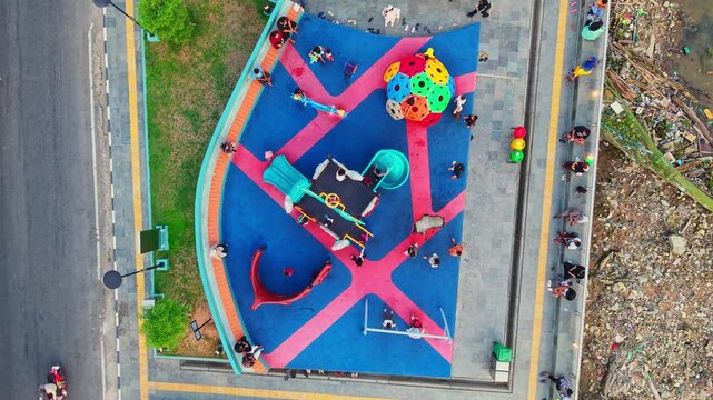 Aerial view of Teras Samarinda 2 playground with colorful rubber flooring, play structures, and people walking along the waterfront in Samarinda, East Kalimantan, Indonesia.