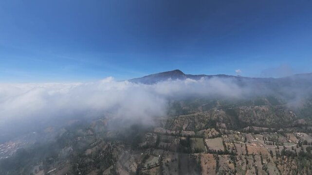 Drone fisheye panorama of cloud inversion over volcanic ridge and patchwork farmland at Cemoro Lawang