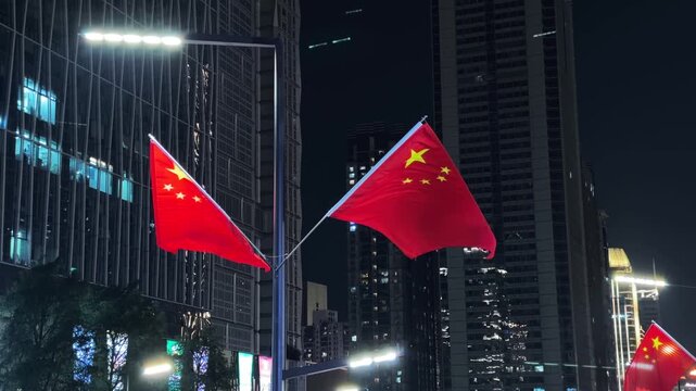 Chinese flags on street lamp against skyscrapers at night
