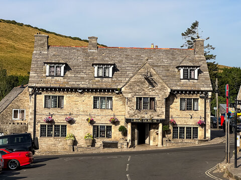 Corfe Castle, Dorset, UK - July 13, 2026. Historic Stone Facade of The Bankes Arms Hotel in Corfe Castle Village. A high-detail horizontal photograph capturing the full front stone facade of The Banke