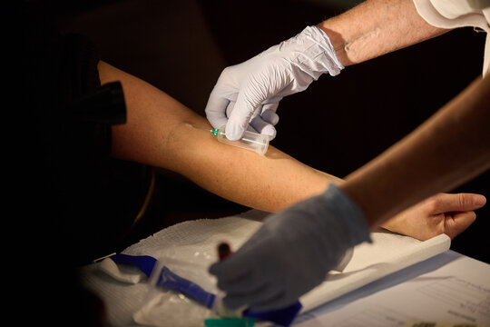 Medical professional drawing blood from a patient's arm using a vacuum tube collection system during a clinical examination