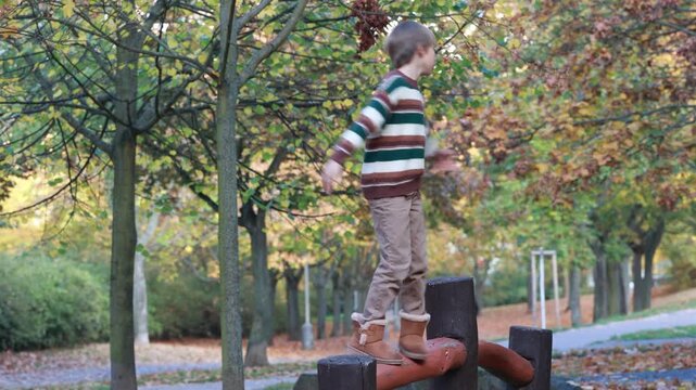 Cute blond child in the park, playing with knitted pumpkins, autumn time