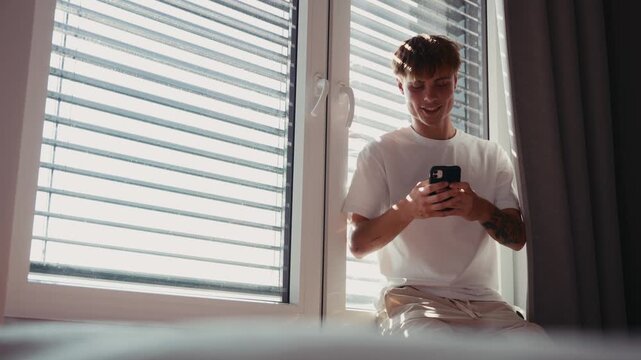 .Young man browsing smartphone during quiet afternoon at home.