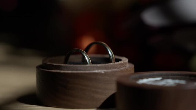 Pair of plain metal bands standing in an open walnut case on a table, a second box beside it.