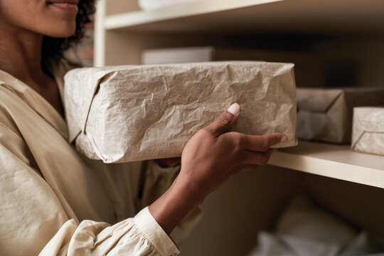 An individual handles a neatly wrapped package, showcasing an organized storage space that highlights the importance of simplicity and mindfulness in everyday life.