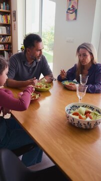 Family enjoying lunch together at dining table in modern home.