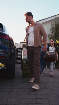 Family packing luggage into car before summer vacation.