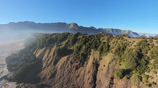 Aerial volcanic landscape. Green slopes rise to rocky peaks near Bromo
