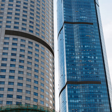 Low angle view of modern high-rise glass skyscrapers in a financial business district. Contemporary glass facade towers reflecting sky, urban architecture background, commercial real estate.