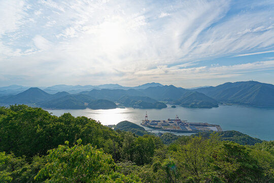 Sunlit bay beneath sweeping clouds and layered mountains