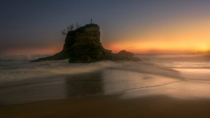 Islet with Neptune statue on El Camello beach during golden sunset with long exposure silky sea water, Santander, Cantabria, Spain © patxi
