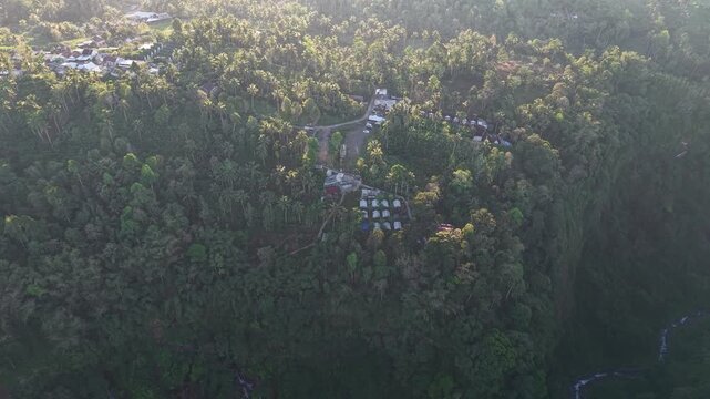 High altitude drone panorama of lush tropical forest, cliffs, waterfalls and hillside village near Tumpak Sewu