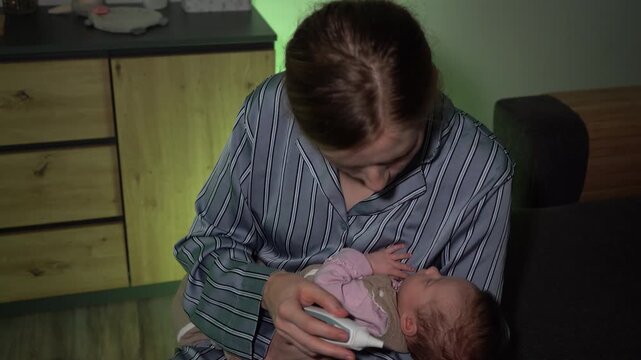 Mother Checking Baby's Temperature with Ear Thermometer in Evening