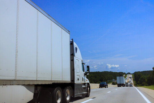 Truck travels down highway surrounded by other vehicles trees