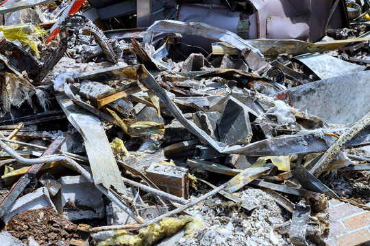 Construction debris covers ground in city area after demolition fragments lie scattered around site.