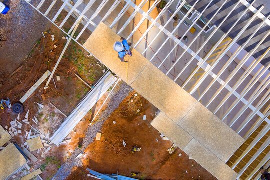 Roofing worker is seen on building site preparing materials for new frame structure