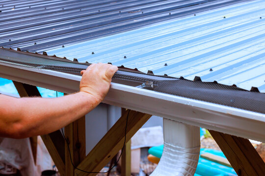 Builder is working on installing metal roof on wooden frame roofing materials tools.