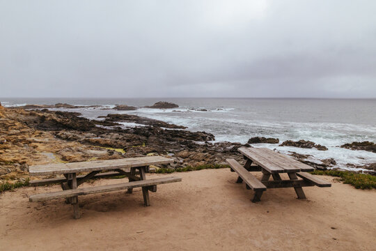 Wooden picnic tables on the cliff overlooking Pacific Ocean coastline at Bean Hollow State Beach